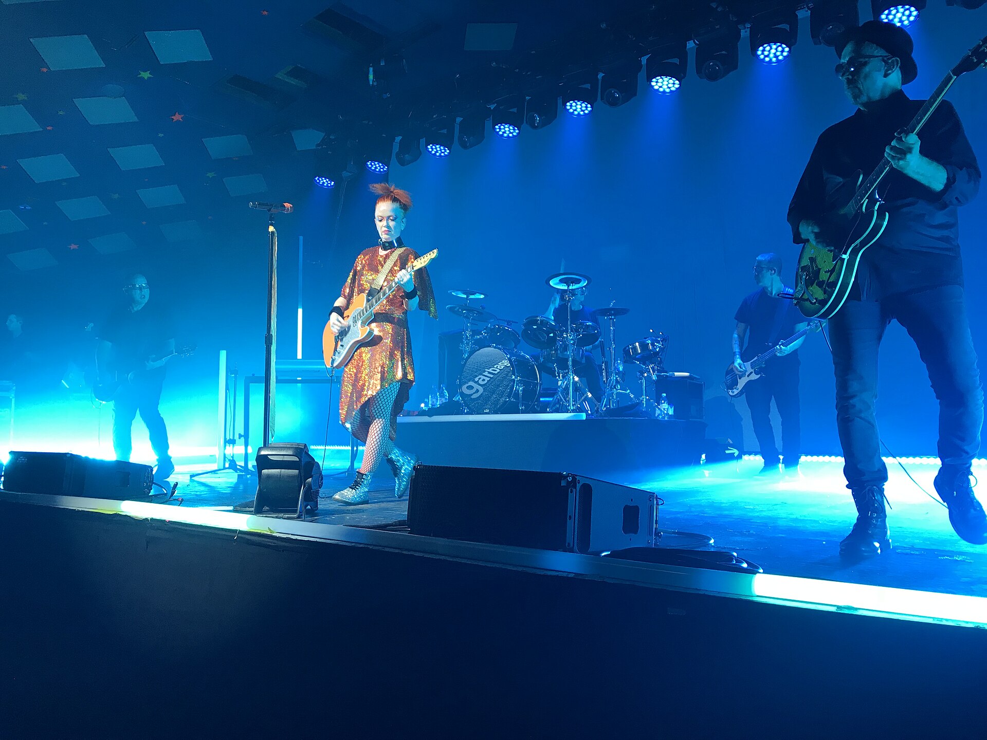 A band performing under blue stage lighting at the Barrowland Ballroom, with the venue's starred ceiling panels visible above