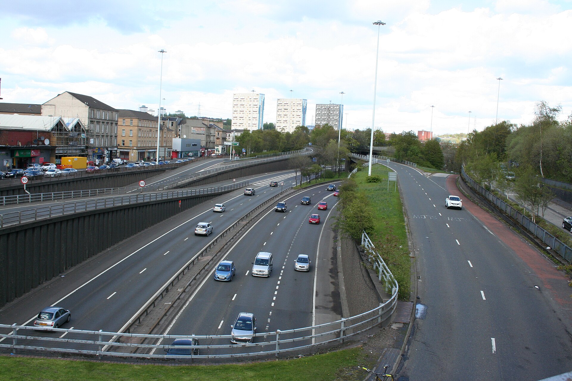 The M8 motorway cutting through Charing Cross, seen from a footbridge above, with traffic, tenements and tower blocks in the distance