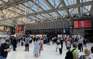 The busy main concourse at Glasgow Central Station under its glazed roof, with departure boards and crowds of passengers