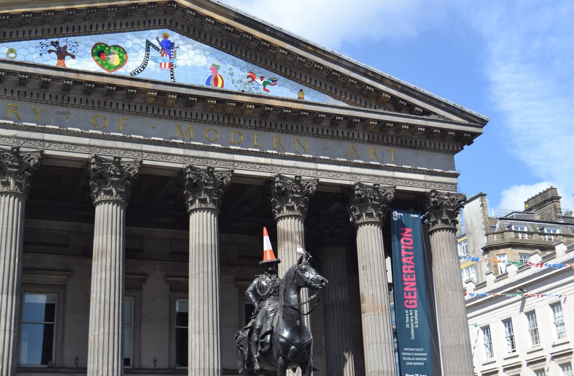 The Duke of Wellington statue, traffic cone on his head, in front of the columned portico of the Gallery of Modern Art on Royal Exchange Square