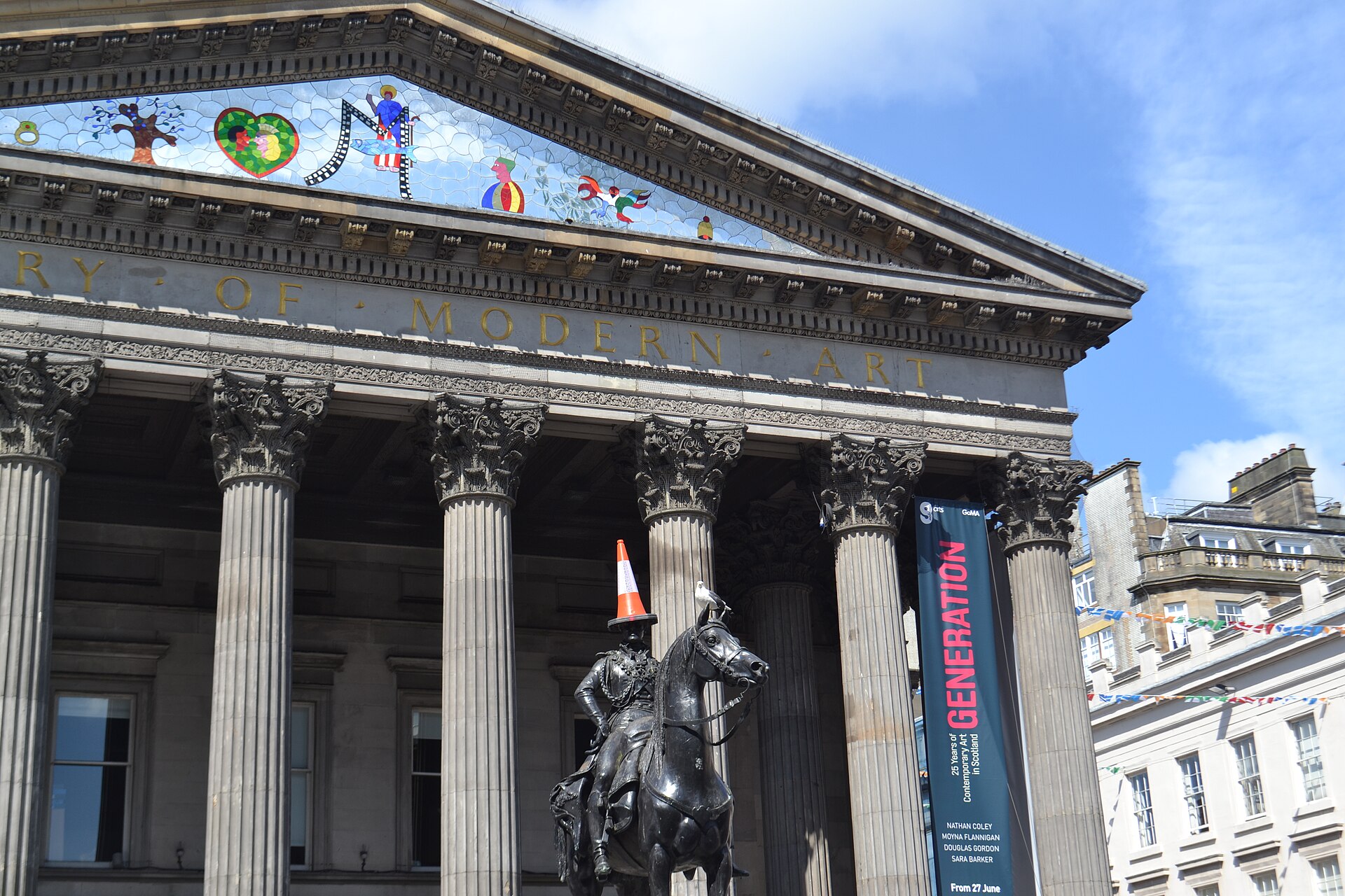 The Duke of Wellington statue, traffic cone on his head, in front of the columned portico of the Gallery of Modern Art on Royal Exchange Square