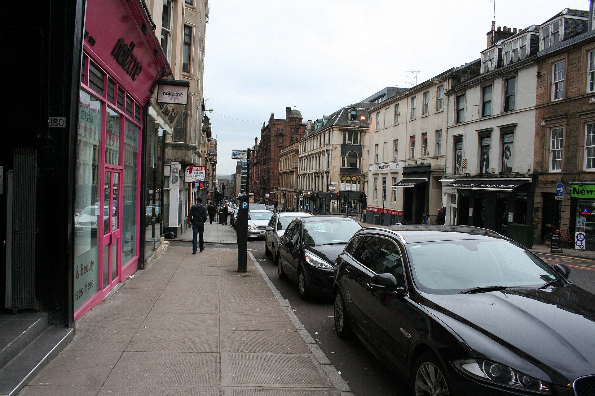 Looking down Hope Street in central Glasgow, lined with sandstone tenements and ground-floor bars and shops