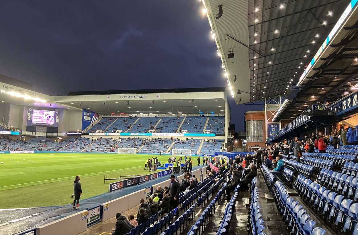 Ibrox Stadium filling up before an evening kick-off, seen from a low seat with the Copland Stand opposite