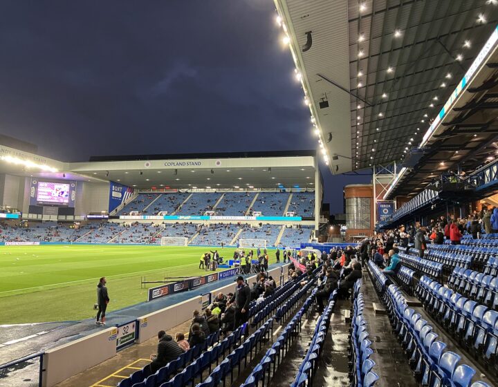 Ibrox Stadium filling up before an evening kick-off, seen from a low seat with the Copland Stand opposite