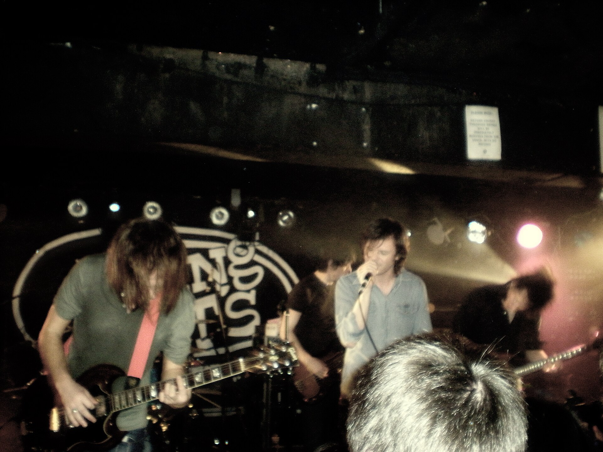 Idlewild on the King Tut's stage, a guitarist in the foreground and the singer at the microphone, with the venue's logo painted on the back wall