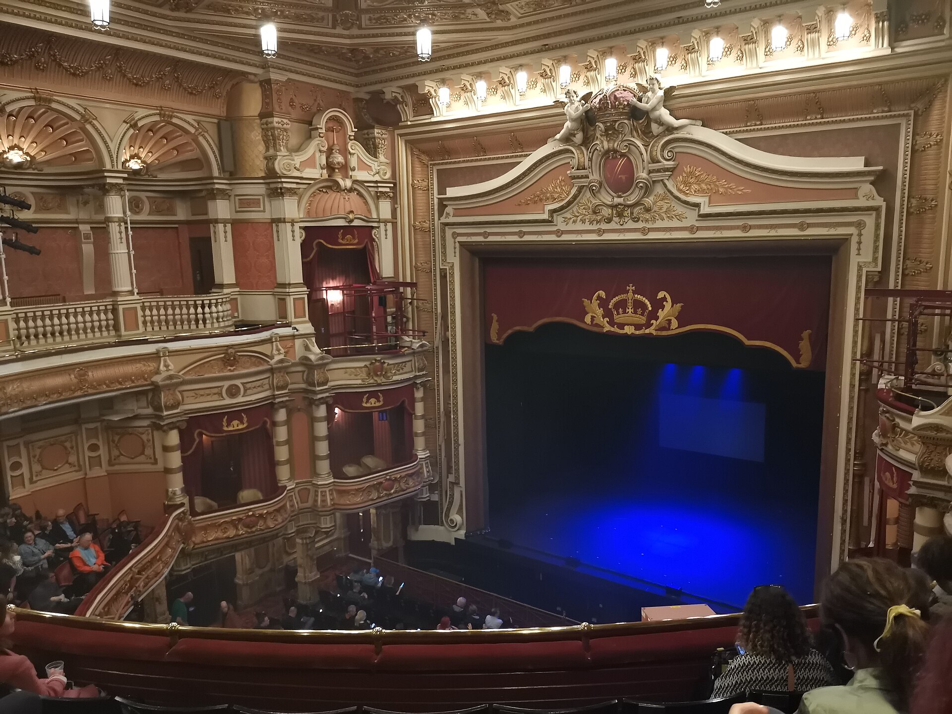 The ornate gilded auditorium of the King's Theatre Glasgow, with red and cream boxes beside the stage, a crown above the proscenium and blue light on the curtain