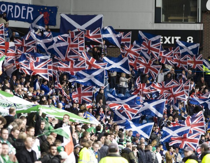 Union flags and saltires on one side of a stand meeting Irish tricolours and green banners on the other during an Old Firm derby