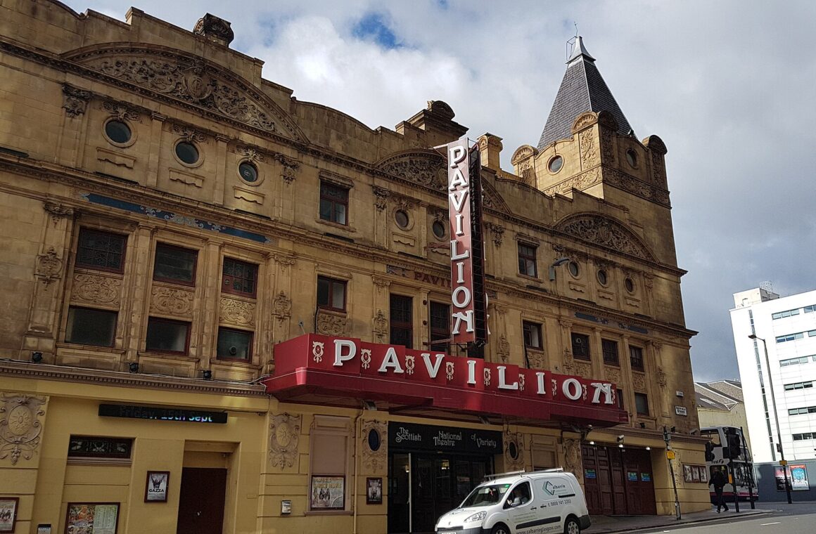 The ornate yellow sandstone frontage of the Pavilion Theatre with its red PAVILION canopy and vertical sign on Renfield Street