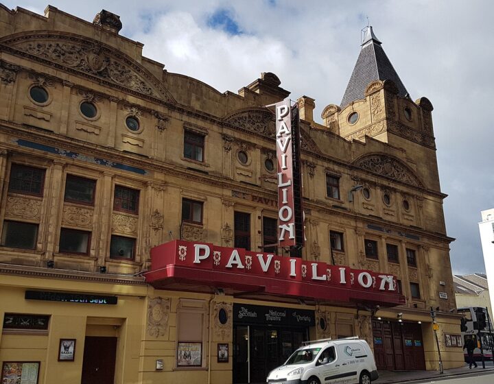 The ornate yellow sandstone frontage of the Pavilion Theatre with its red PAVILION canopy and vertical sign on Renfield Street