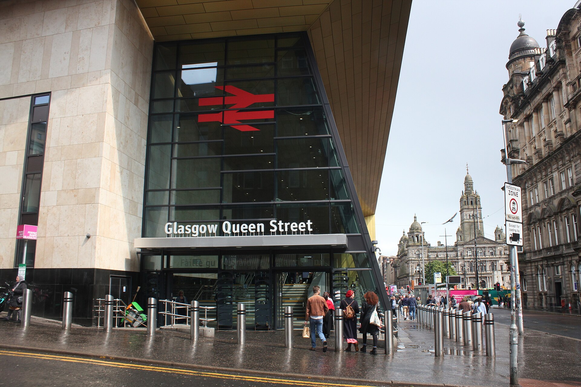The glass and steel Dundas Street entrance to Glasgow Queen Street station, with pedestrians outside on a grey day
