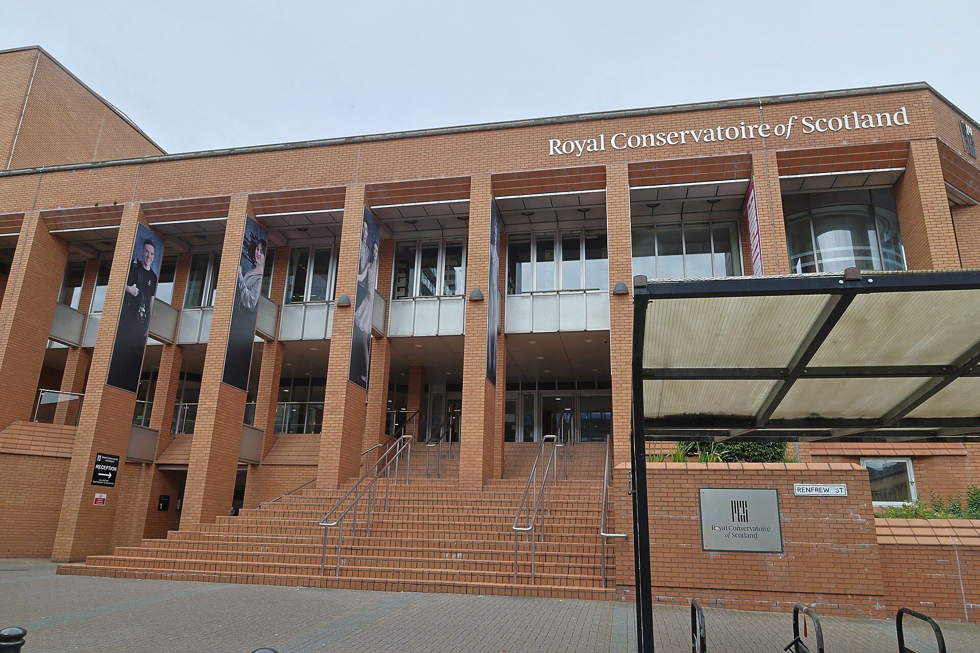 The red-brick frontage of the Royal Conservatoire of Scotland on Renfrew Street, with wide steps and tall banners between the columns