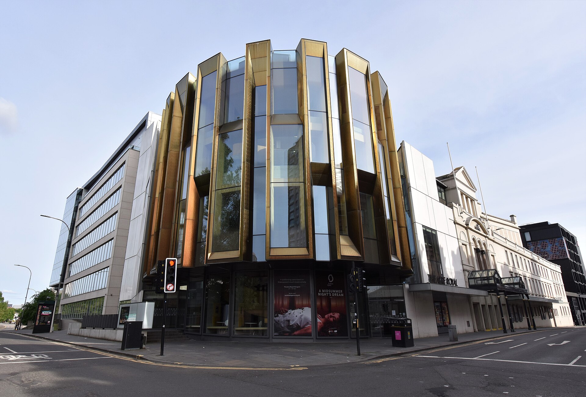 The modern glass and gold-finned corner extension of the Theatre Royal Glasgow beside its older white stone frontage on Hope Street