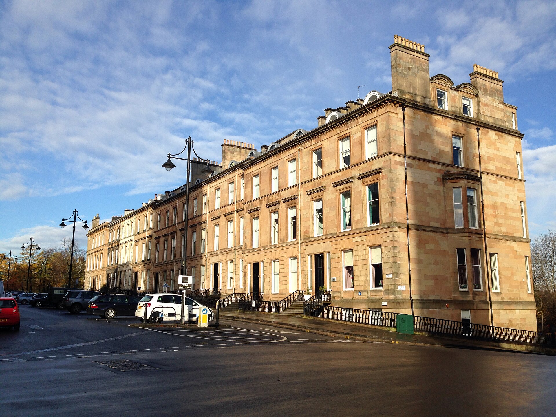 Sunlit sandstone terrace curving along Park Circus Place in Glasgow's West End, with old-style lamp posts